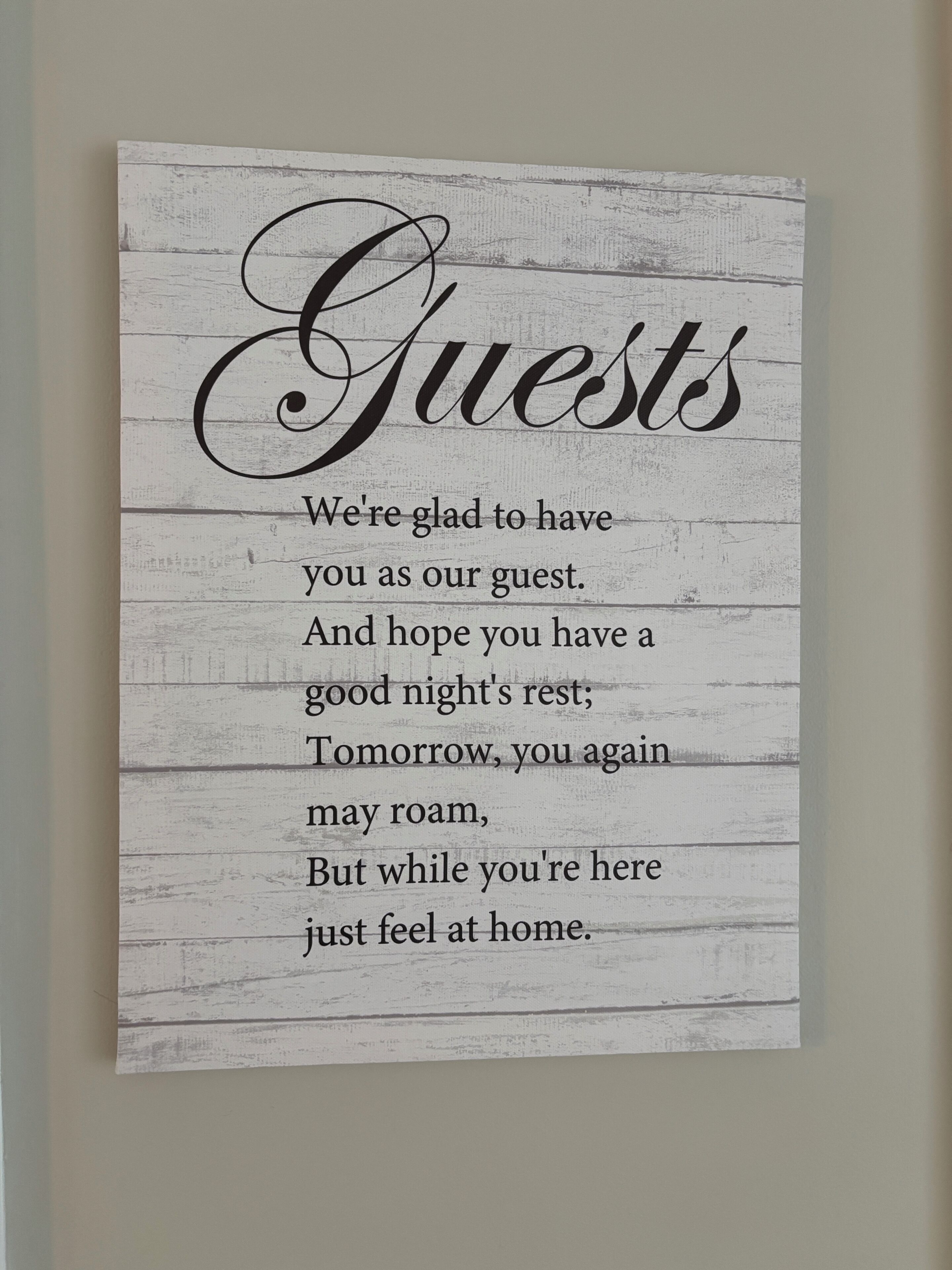 A framed sign with a rustic wooden background and black text.