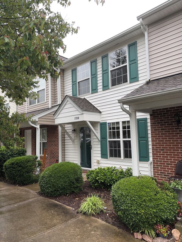 A two-story residential building with a brick facade and white siding. - Convenient Charming Townhouse (Raleigh)
