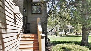 A wooden staircase leading to a house's front door, surrounded by a well-maintained lawn and trees. - Fairway Village 25 - SHARC + Condo Pool, Hot Tub, Near Golf Course, A/C (Sunriver)