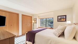 A bedroom with a bed, wooden wardrobe, a desk, a window with blinds, and a wall-mounted TV. - Fairway Village 25 - SHARC + Condo Pool, Hot Tub, Near Golf Course, A/C (Sunriver)