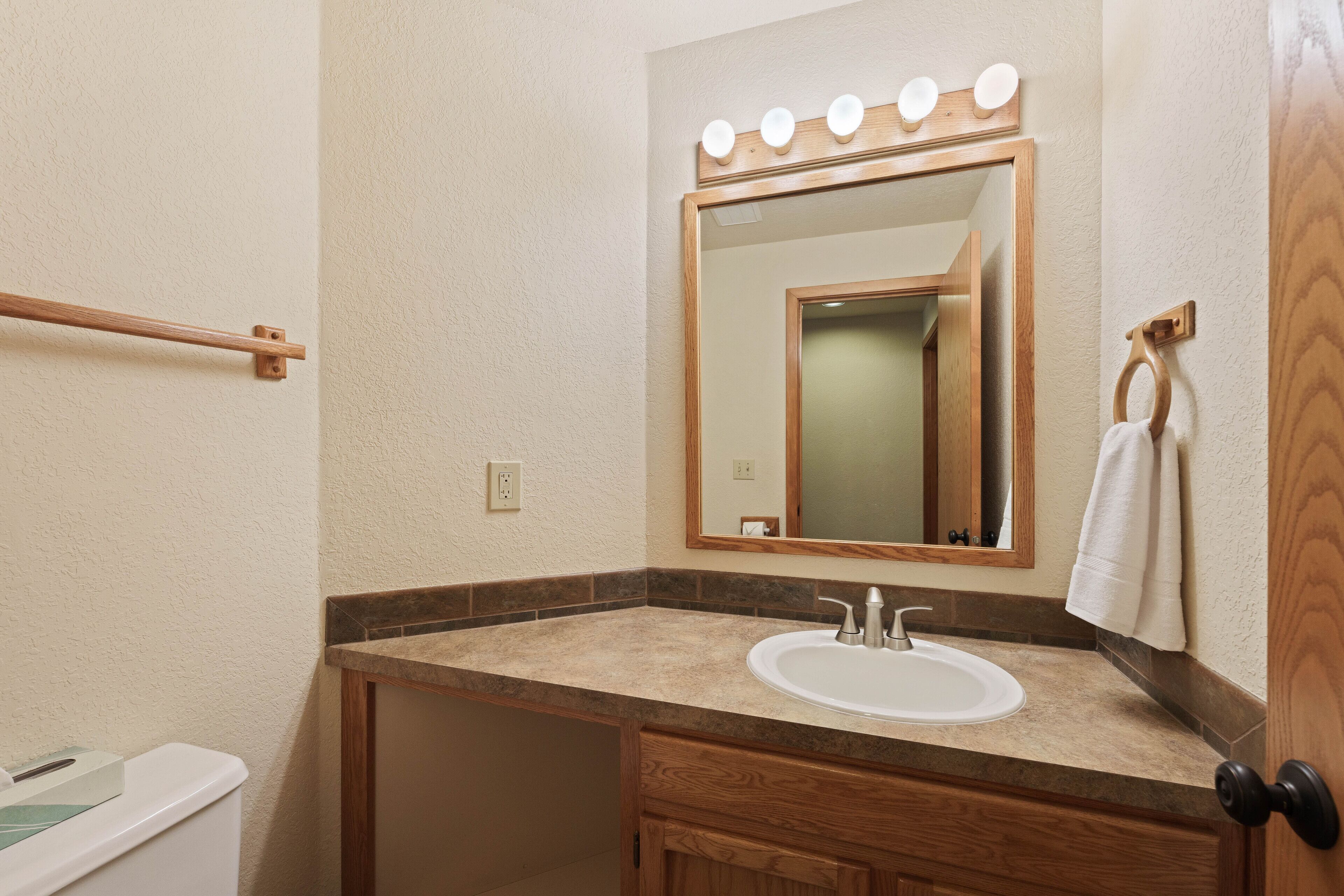 Une salle de bain avec un meuble-lavabo, un évier, un miroir et des luminaires au-dessus du miroir.