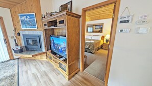 Ett mysigt vardagsrum med en öppen spis, en TV-möbel i trä och en tv.