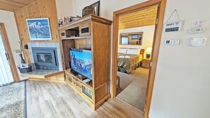 A cozy living room with a fireplace, wooden entertainment unit, and a TV.