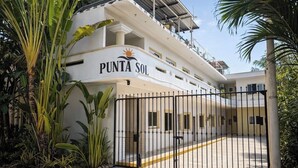 Un edificio a più piani con un cartello che riporta 'PUNTA SOL' e un ingresso recintato.