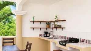 Una cucina compatta con piano cottura a gas, mensole in legno e un'area pranzo con sedie.