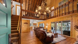 A spacious wooden interior with a staircase, a leather sofa, and a chandelier. - McKinney Lakeview Lodge in Homewood (Tahoma)