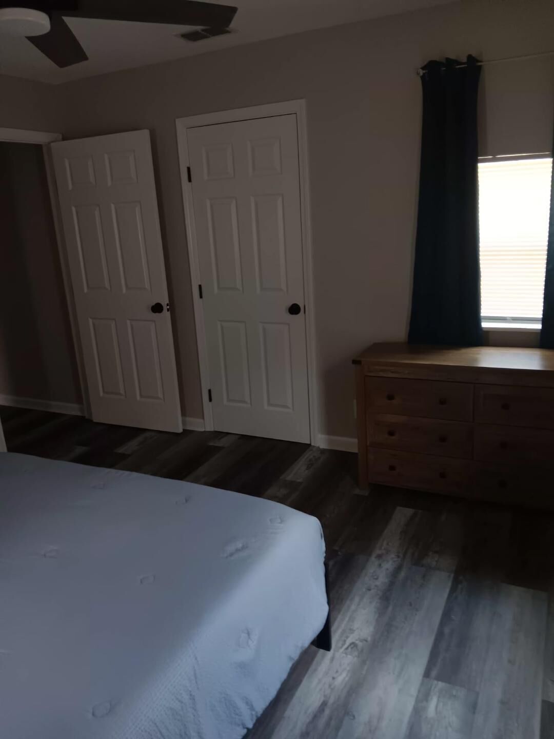A bedroom with a bed, a dresser, and two doors.