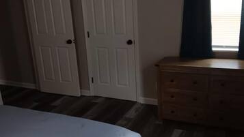 A bedroom with a bed, a dresser, and two doors.