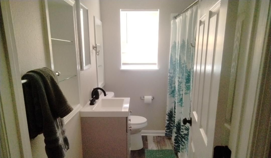 Ein schmales Badezimmer mit Toilette, Waschbecken und einem Fenster.