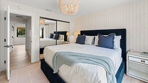 A bedroom with a large bed, a chandelier, a mirror, and a herringbone-patterned wall. - New Modern Luxury, 3/2 Fam Friendly, BBQ, Central! (Encinitas)