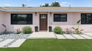 A modern two-story house with a beige facade, large windows, and a well-maintained front yard with a stone pathway and greenery. - New Modern Luxury, 3/2 Fam Friendly, BBQ, Central! (Encinitas)