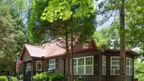 A cabin with a metal roof, surrounded by trees and a flag.