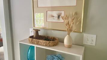 A white shelving unit with a framed fish illustration, a decorative bowl, and a vase.