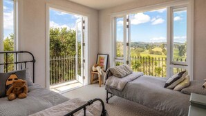 A bedroom with two beds, large windows, and a view of the countryside.