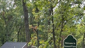 Une cabane avec une pancarte indiquant : « Bienvenue à la cabane SummitView 1383 », située dans une zone boisée.