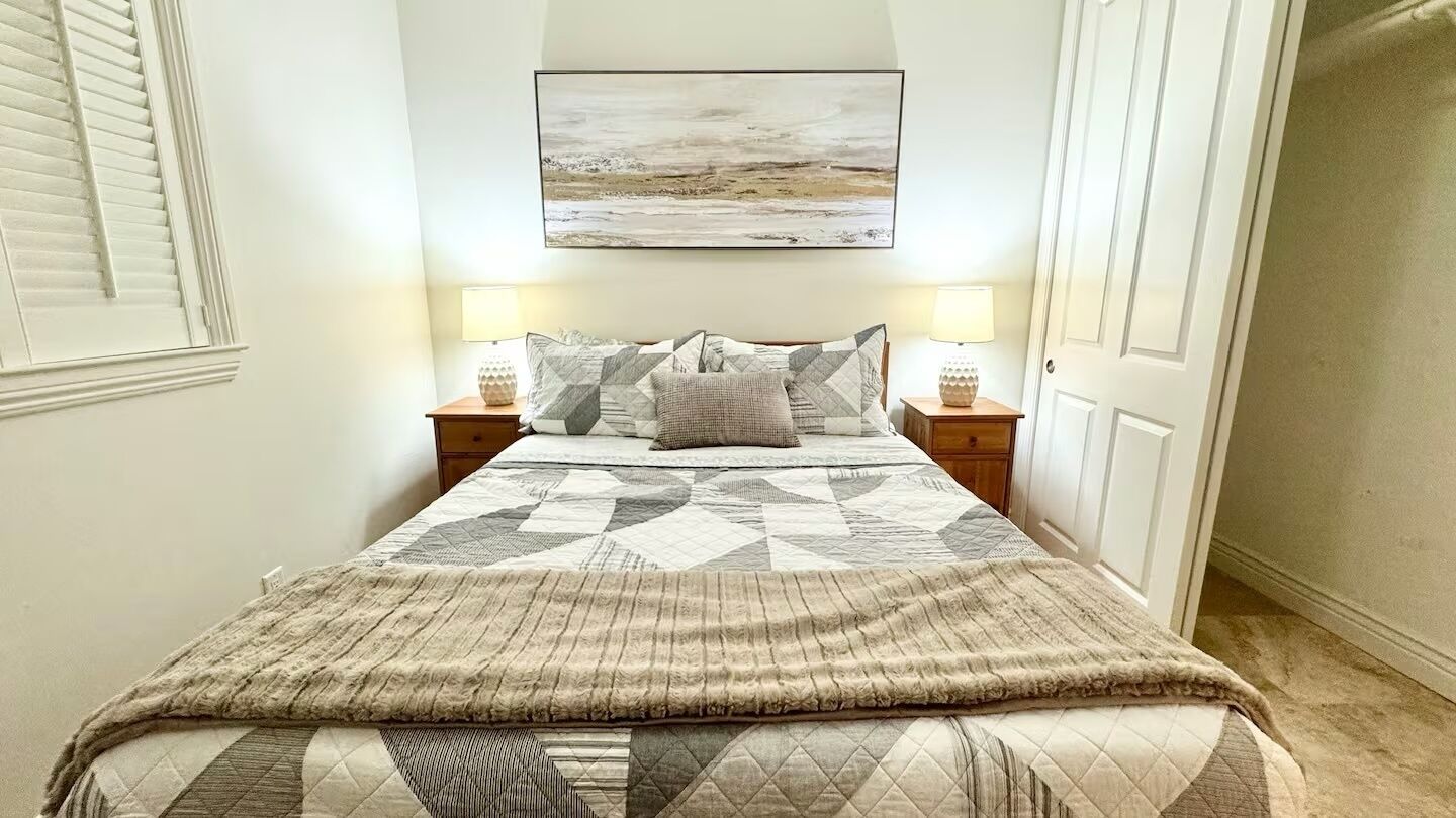 Ein Schlafzimmer mit einem Bett, zwei Nachttischen, einem Wandbild und einer Tür.