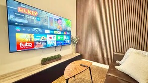 Televisione a schermo piatto montata a parete che mostra un'interfaccia di servizio di streaming con diversi canali e il logo 'fubo'.