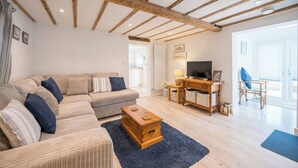 Un salon comprenant un canapé, une table basse en bois, un meuble pour la télévision et une vue sur l’extérieur.