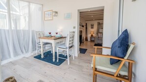 Un salon moderne avec un coin repas, comprenant une table en bois, des chaises blanches et un tapis bleu.