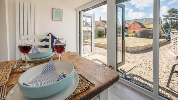 Un coin repas avec une table dressée pour deux personnes, deux verres à vin, un bol et un set de table.