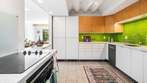Une cuisine moderne avec des armoires blanches, une cuisinière noire et un revêtement mural vert.