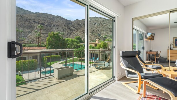Un balcon avec une porte vitrée, une piscine et un paysage montagneux en arrière-plan.