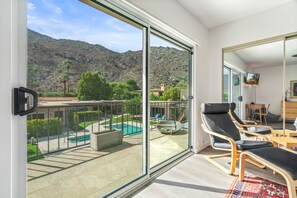 A balcony with a glass door, a pool, and a mountainous landscape in the background. - Heart of Downtown PS 2Bed 2.5Bath (Palm Springs)