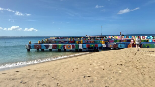 A beach with colorful painted structures extending into the water.
