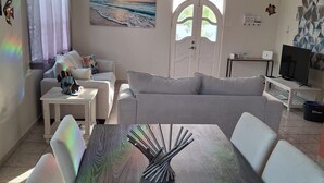 A modern living room with a dining table, sofas, and a TV.