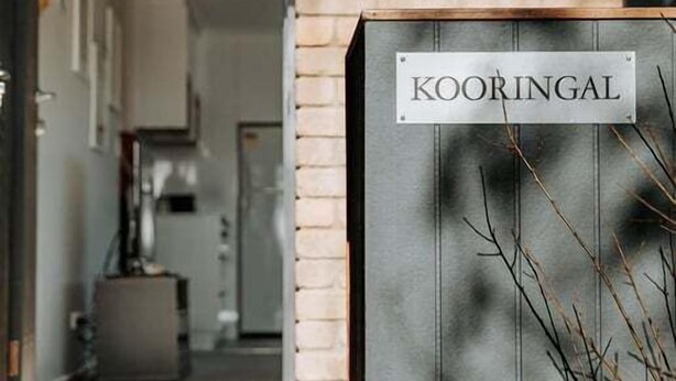 Un escalier en bois mène à une porte portant l’inscription « KOORINGAL ».