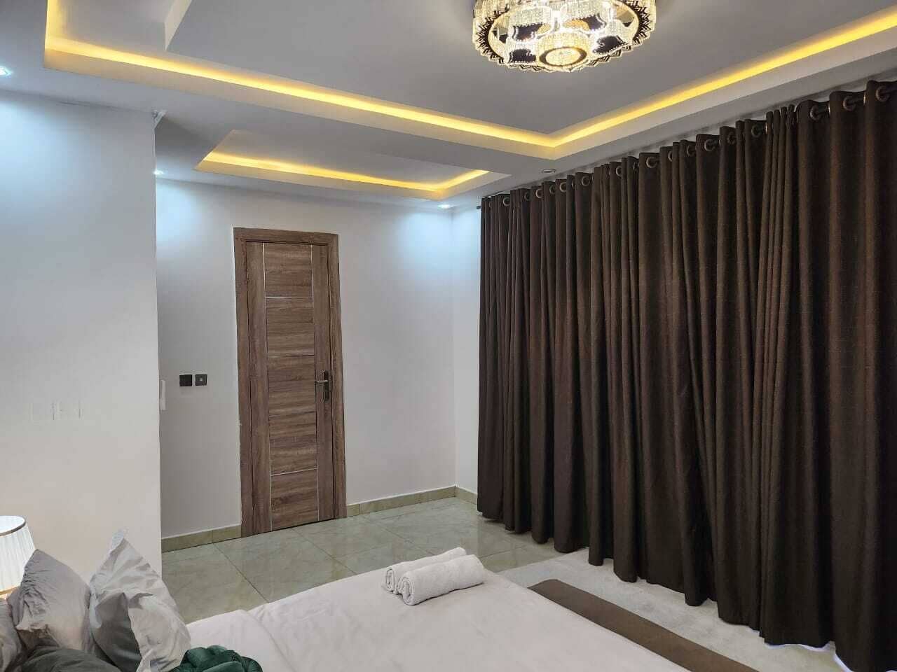 Een hotelkamer met een bed, een houten deur en een gordijn.