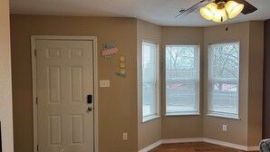 A room with a door, a ceiling fan, and two windows with blinds. - New 2 bedroom home near Downtown (West Plains)