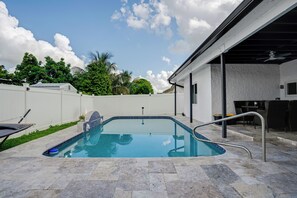 A swimming pool with a tiled deck, surrounded by a white fence and greenery. - Luxe by Jenn • 3BR Retreat w/ Heated Pool (Lauderdale Lakes)
