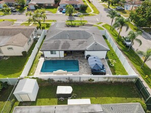 A residential property with a swimming pool, fenced yard, and a detached garage. - Luxe by Jenn • 3BR Retreat w/ Heated Pool (Lauderdale Lakes)