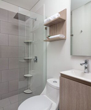 Une salle de bain moderne dotée d’une douche à parois de verre, de toilettes et d’un meuble-lavabo avec un miroir.