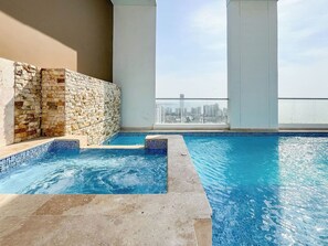 Une piscine sur le toit, avec un mur en pierre et une vue sur le panorama urbain.