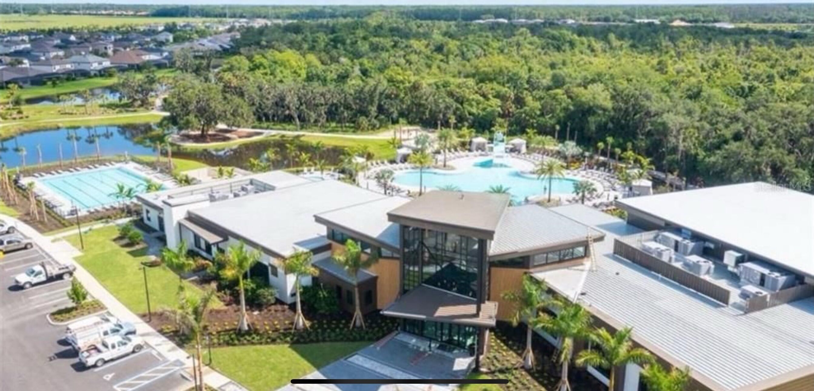 Un hotel moderno con piscina sul tetto, una grande piscina esterna e un'area parcheggio.
