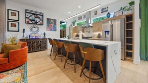 A modern kitchen with a central island, bar stools, and a red sofa. - Luxury 4BR Near BeltLine Hot Tub Game Room  Sleeps 10 (Atlanta)