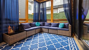 A corner seating area with a blue patterned rug, dark blue curtains, and wicker furniture. - Luxury 4BR Near BeltLine Hot Tub Game Room  Sleeps 10 (Atlanta)