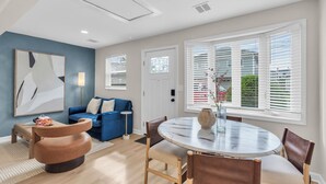 A modern living room with a blue accent wall, a round dining table, and a blue sofa. - Professionally Managed | Walk to Beach (Seaside Heights)