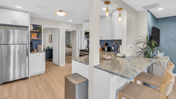 A modern kitchen with white cabinets, a stainless steel refrigerator, a marble countertop, and a built-in oven. - Professionally Managed | Walk to Beach (Seaside Heights)