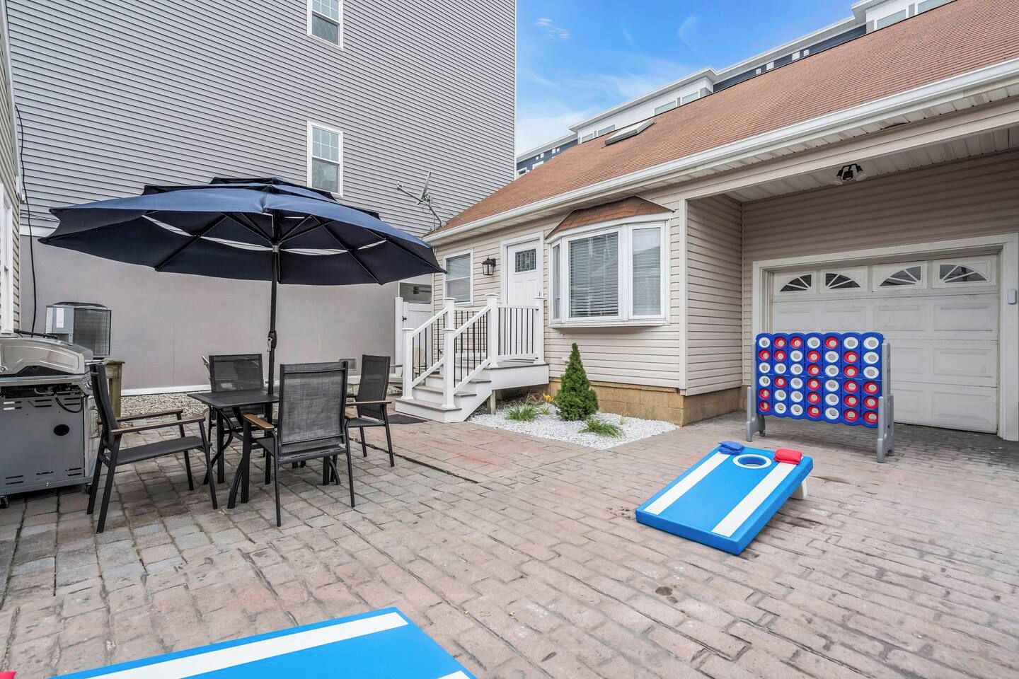 A patio with a grill, outdoor seating, and a game table.