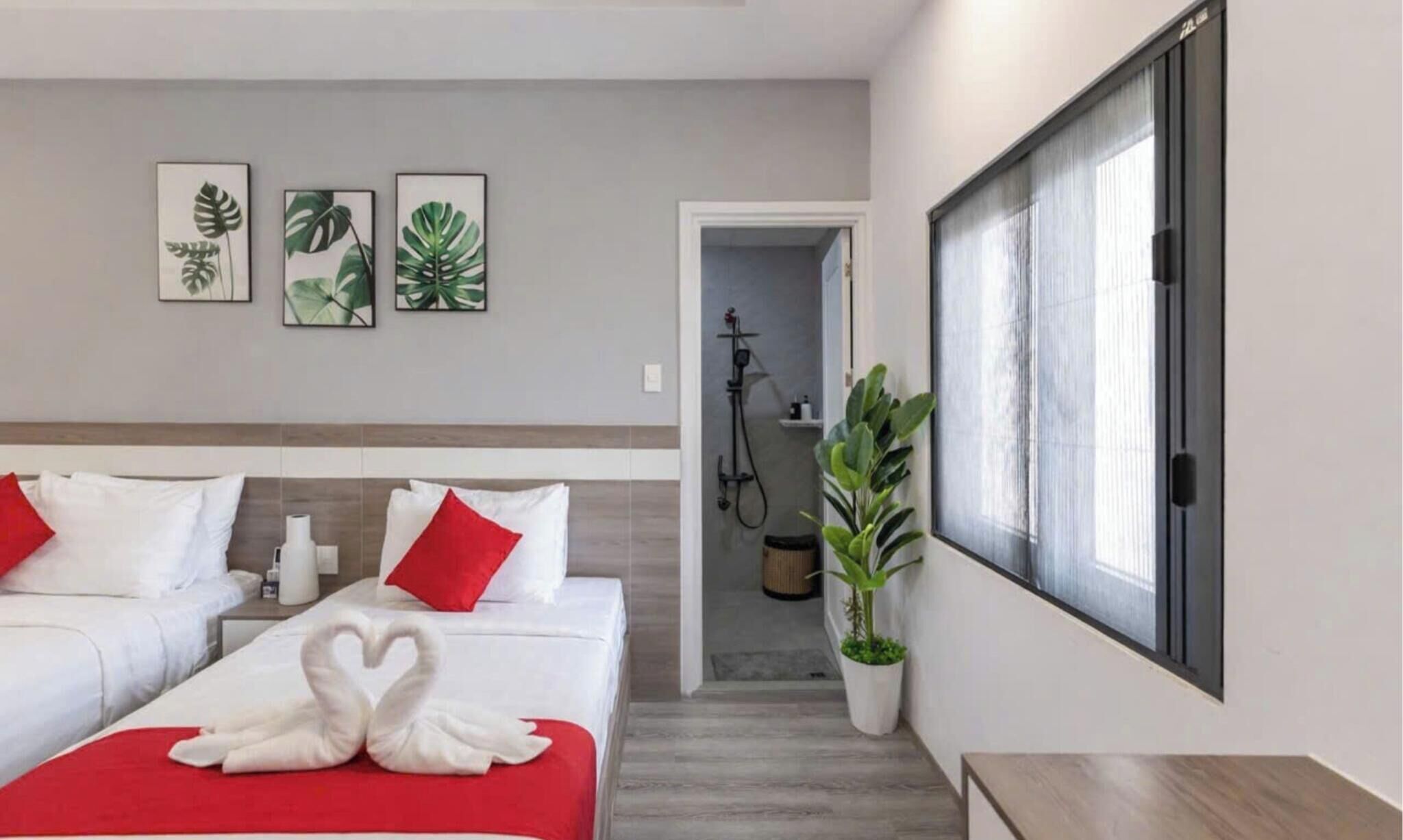 A hotel room with two beds, a shower area, and a large window.