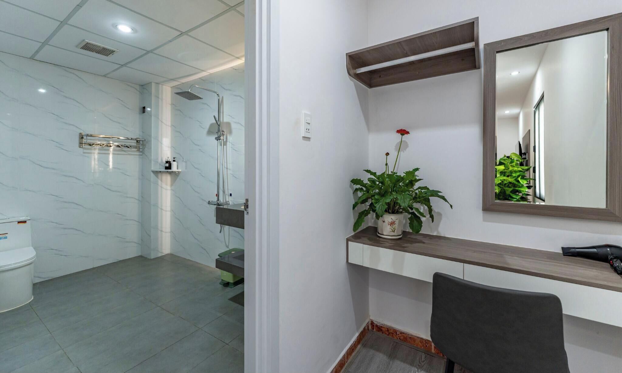 Un baño con ducha, inodoro y tocador con espejo y planta.
