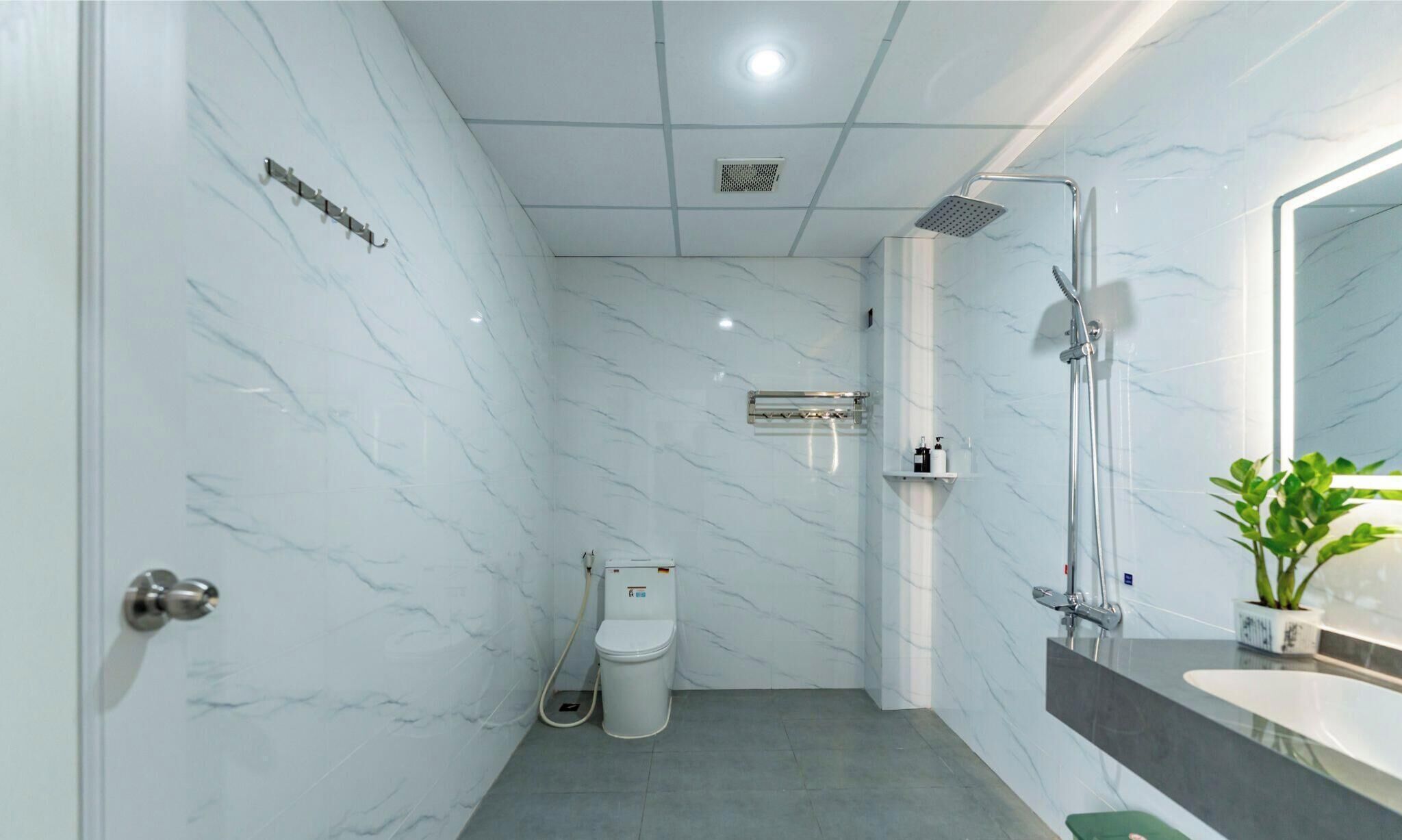 Un bagno moderno con pareti in marmo, un water, una doccia e un lavabo con specchio.