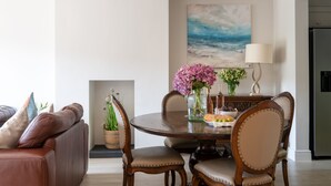 Un coin repas avec une table ronde, des chaises et un vase de fleurs.