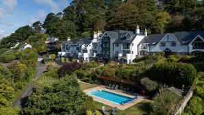 Une grande maison à plusieurs étages, dotée d’une piscine, entourée d’une végétation luxuriante et d’arbres.