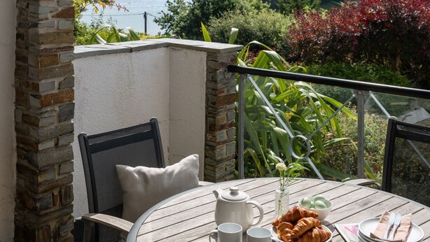 Une table ronde avec vue sur la mer, un mur en pierre et une balustrade de balcon.