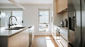 Eine moderne Küche mit weißen Schränken, einem Edelstahlkühlschrank und einem Fenster für natürliches Licht.