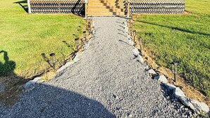 A two-story house with a covered porch, a gravel driveway, and a grassy yard.